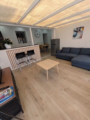 A modern living room with a sofa, a coffee table, and a dining area with chairs and a table.
