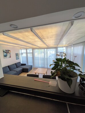 A modern living room with a sectional sofa, a coffee table, and a potted plant. - Apartment RESTO GRAND (Landéda)