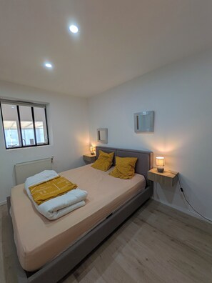 A bedroom with a bed, bedside lamps, a window, and a radiator.