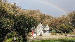 A stone house with a stone roof, surrounded by trees and a gravel driveway. - Lake View Villa - Rosecraddoc Manor (Liskeard)