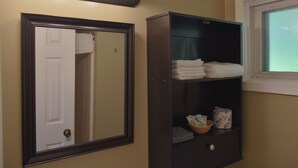 Un baño con un espejo grande, un tocador con estante y una ventana.