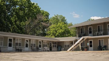 A motel with a two-story structure, a covered outdoor seating area, and a staircase leading to the upper floor.