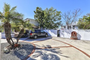 A residential driveway with a parked SUV, palm trees, and a white fence. - Secluded Garden Oasis, Steps to Main Beach, Sauna & Parking (Laguna Beach)