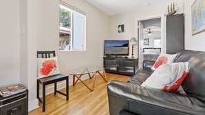 Una sala de estar con un sofá de cuero, una mesa de centro de vidrio y un televisor.