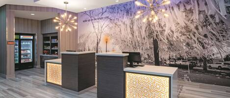 Uma área de recepção moderna com um mural de árvores e uma citação na parede, um balcão de atendimento e um expositor refrigerado.