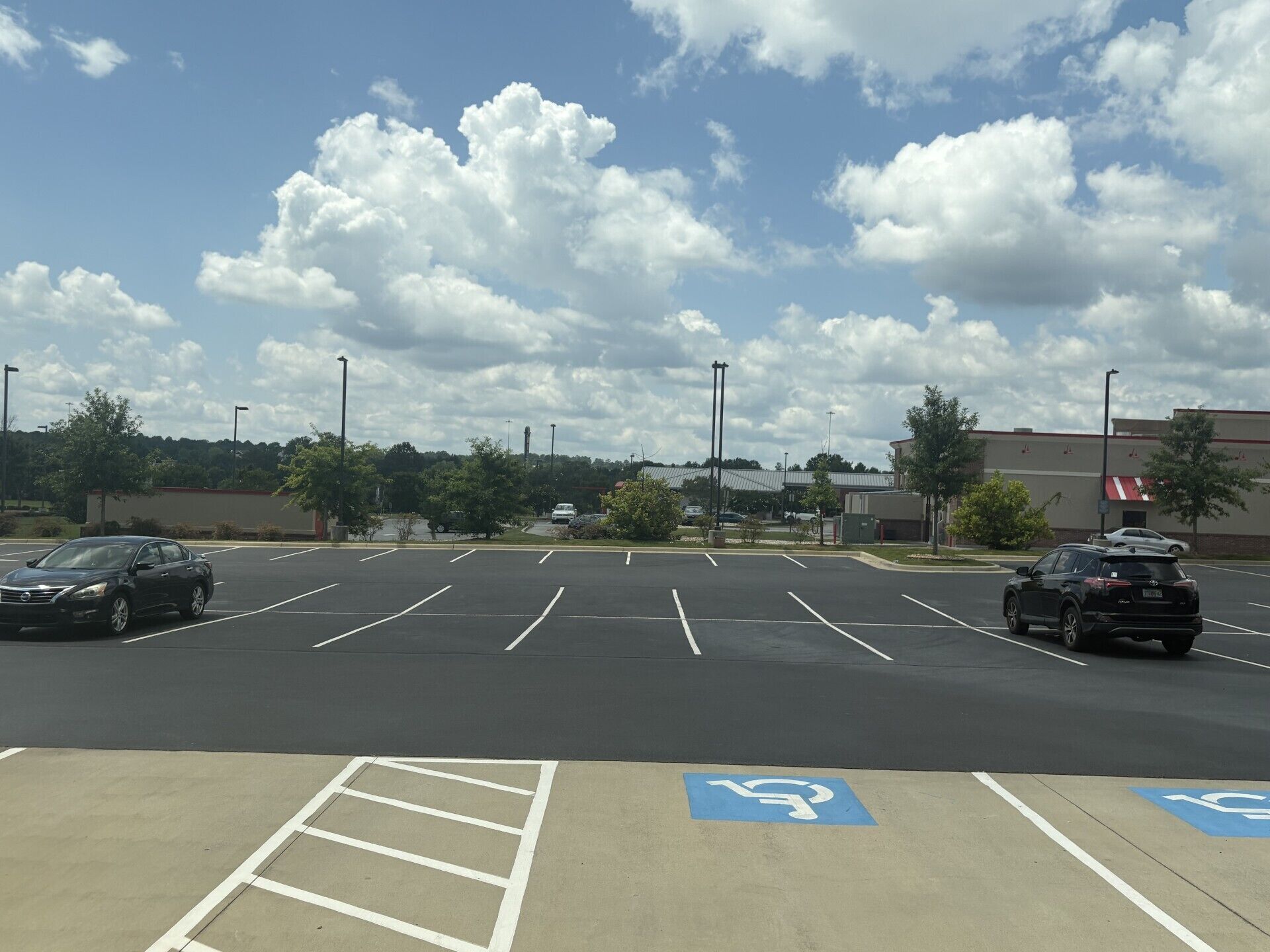 A parking lot with marked handicapped spaces, a clear sky, and a building in the background.