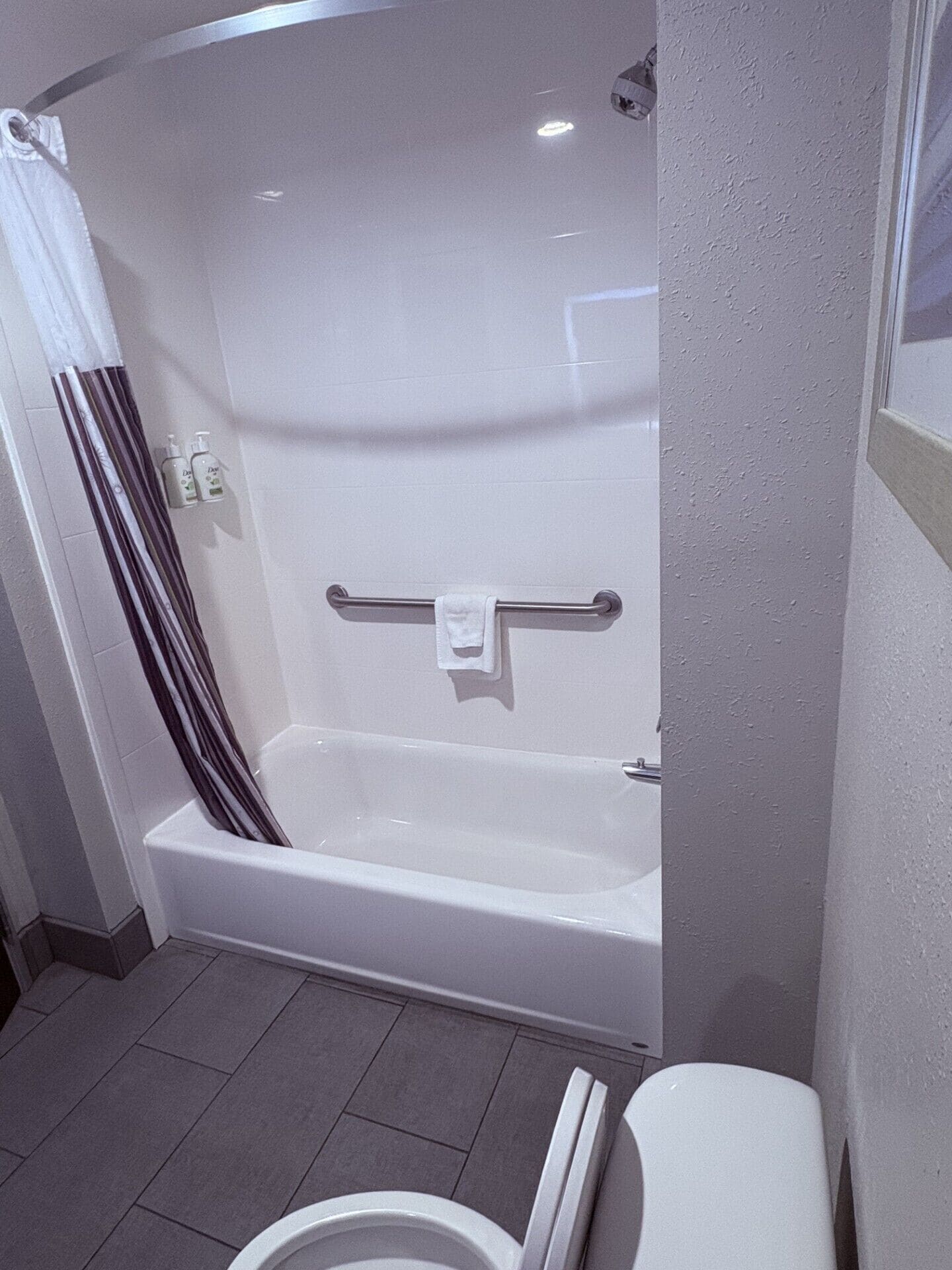 Un baño moderno con una bañera blanca, zona de ducha y retrete.