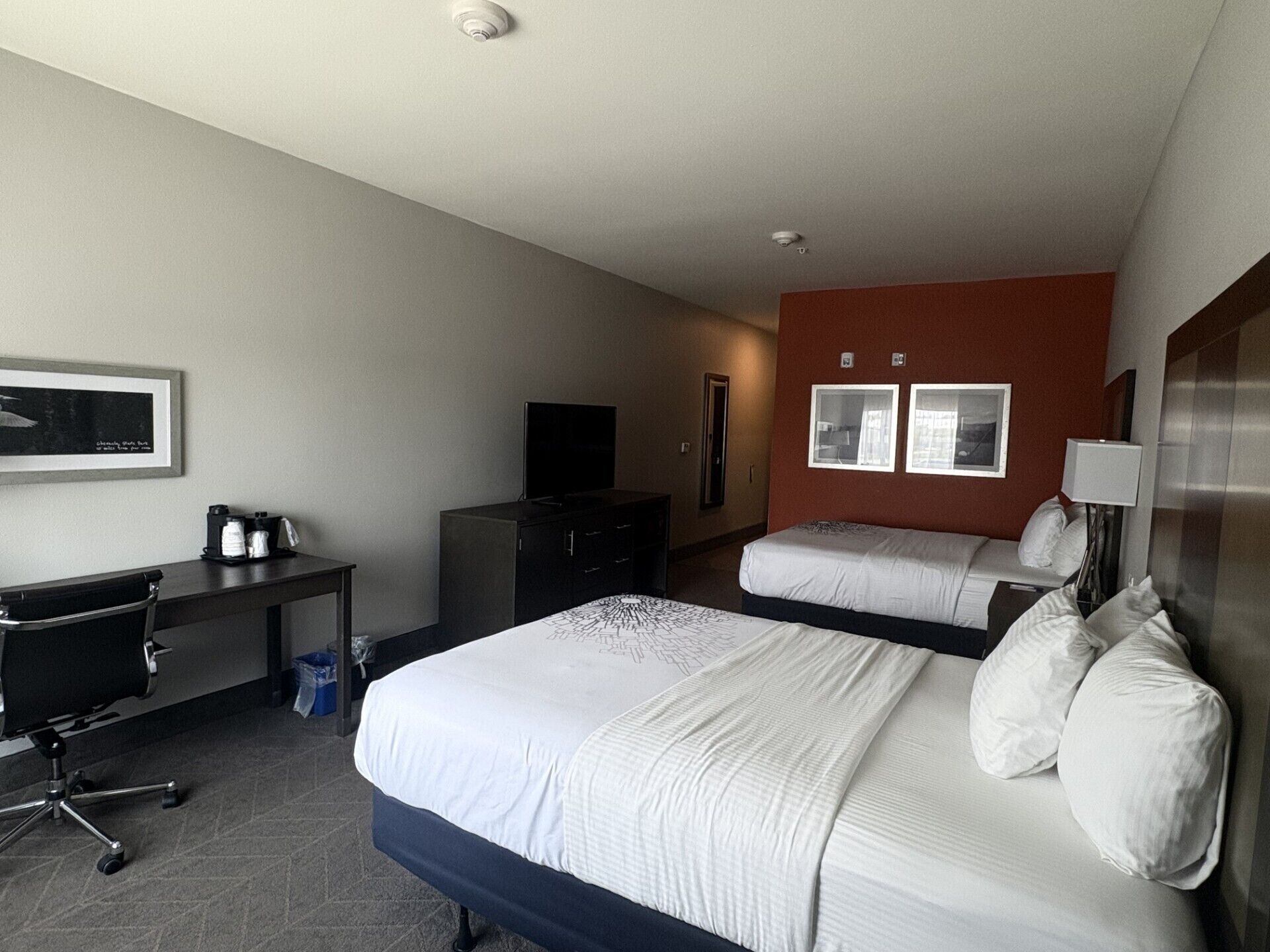 Une chambre d’hôtel avec un grand lit, un bureau, une chaise, une télévision et une petite fenêtre.