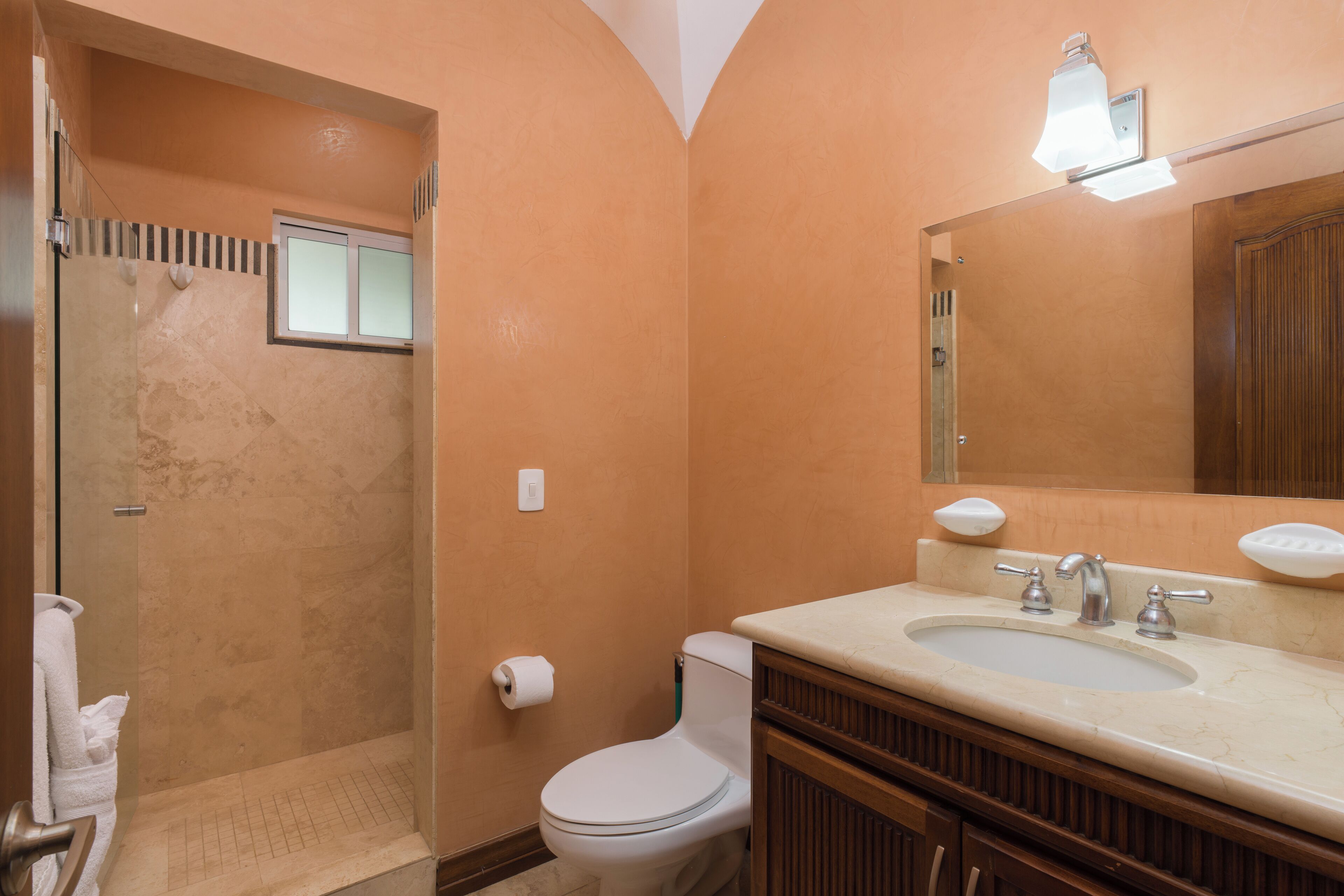 Een badkamer met douche, toilet, wastafel en spiegel.