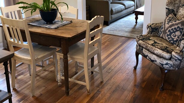 A dining area with a wooden table and chairs, a potted plant, and a patterned armchair. - The Wilson House  Beautiful Downtown Murfreesboro Cottage Close to MTSU / I 24 (Murfreesboro)