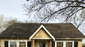 A single-story house with a front porch, a number '1116' on the door, and a small front yard with grass and a concrete path leading to the door. - The Wilson House  Beautiful Downtown Murfreesboro Cottage Close to MTSU / I 24 (Murfreesboro)