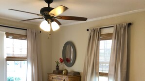 A bedroom with a bed, wooden dresser, ceiling fan, and two windows with curtains. - The Wilson House  Beautiful Downtown Murfreesboro Cottage Close to MTSU / I 24 (Murfreesboro)
