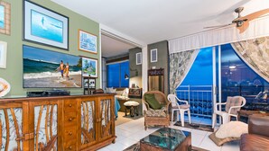 Un salon doté d’un grand téléviseur, d’un meuble en bois, d’une table basse en verre et d’un balcon avec vue.