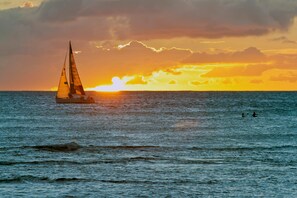 Un voilier sur une eau calme, avec un coucher de soleil en arrière-plan.