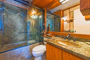 Une salle de bain avec une douche à parois de verre, un lavabo doté d’un plan de toilette en bois et des toilettes.