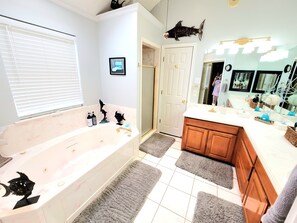 Een bad/douchecombinatie, een bubbelbad, een haardroger, handdoeken