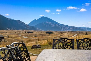 A table and chairs with a mountainous landscape in the background.