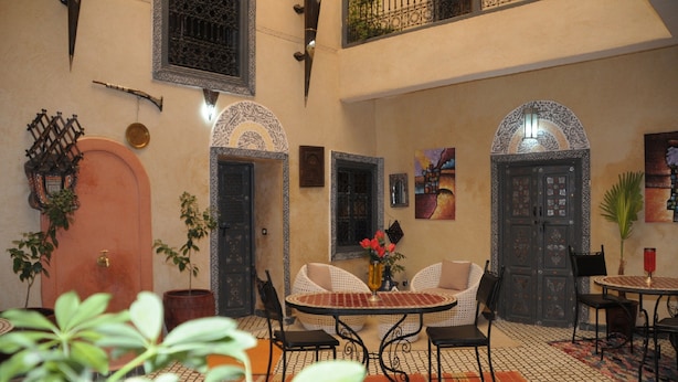 A traditional interior with a high ceiling, ornate doors, and a central round table with chairs. - Riad belko - Hostel (Marrakech)