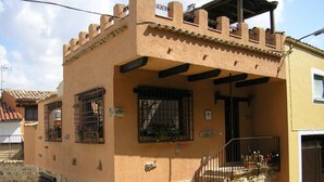 Il s’agit d’un bâtiment à deux étages, avec une base en pierre et une partie supérieure de couleur beige. Il est doté d’un balcon avec des rampes en métal et d’un petit espace porche.