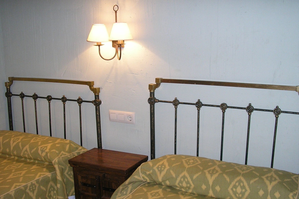Een kamer met twee bedden, een nachtkastje en een lamp aan de muur.