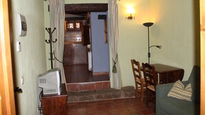 Un salon chaleureux avec une table en bois, un canapé et un escalier menant à la salle à manger.