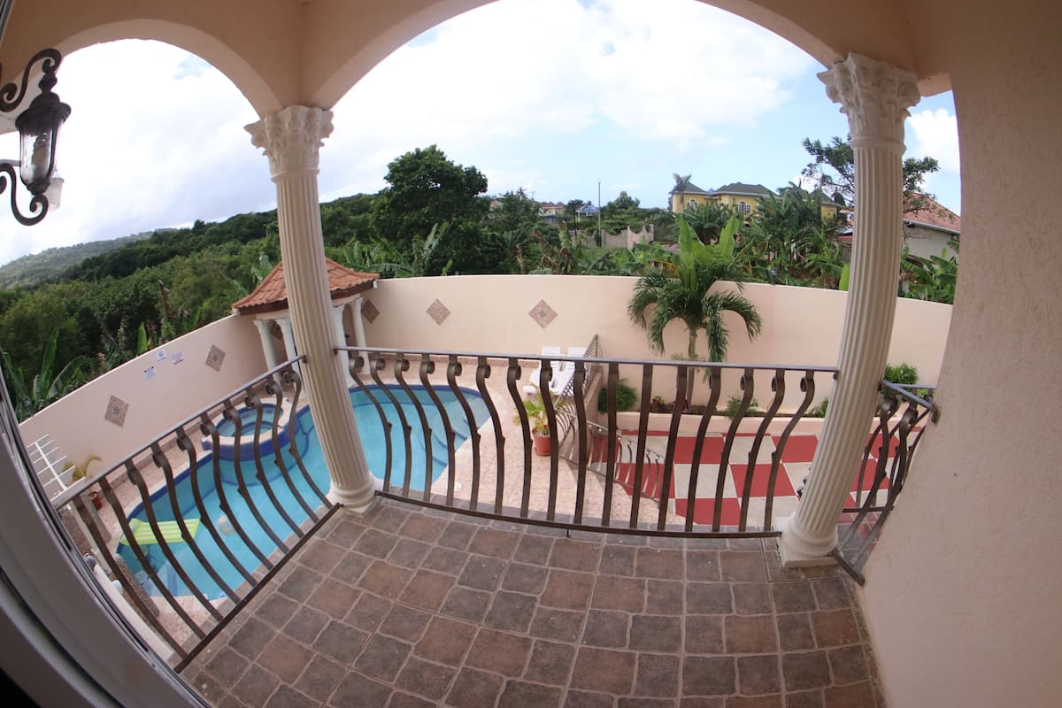 Un balcon avec une piscine, des plantes en pot et une vue sur une colline.