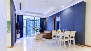 A modern living room with a dining area, large windows, and a view of tall buildings.