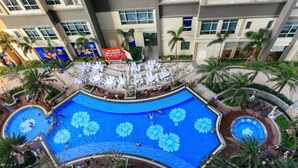 A rooftop pool with flower-shaped designs, surrounded by lounge chairs and palm trees.