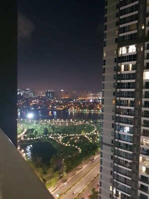 Paisagem urbana noturna com rio, ruas iluminadas e um arranha-céu.