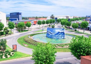 A roundabout with a central fountain, surrounded by trees and a road. - Hotel Silvia (Castello d'Empuries)