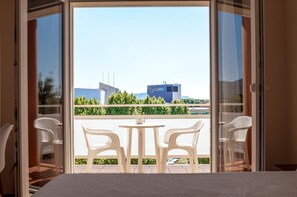 A balcony with a table and chairs, a view of a building with a sign, and a clear sky. - Hotel Silvia (Castello d'Empuries)