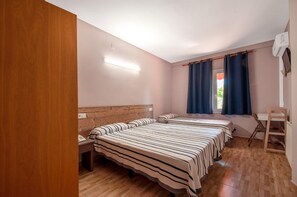 Een slaapkamer met twee bedden, een houten hoofdbord, een bureau en een stoel.
