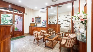 A hotel lobby with wooden furniture, a reception desk, and a large mirror. - Hotel Silvia (Castello d'Empuries)
