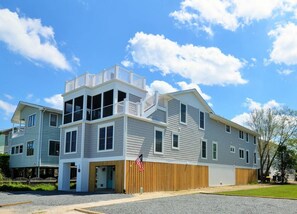 Um edifício residencial de dois andares com uma varanda no andar superior, cerca de madeira e uma bandeira americana.