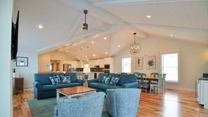 A spacious living area with a blue sofa set, a wooden coffee table, and a dining table with chairs.
