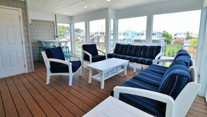 A covered outdoor seating area with white furniture and a view of the neighborhood.