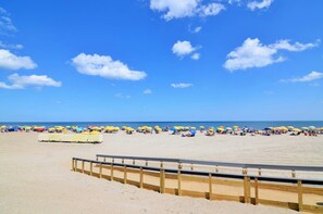 Ein Strand mit einer Holzpromenade und Sonnenschirmen.