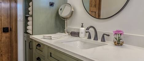 A bathroom with a white sink, a mirror, a towel rack, and a wooden cabinet.
