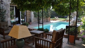 Ein Patio mit Pool, Holzmöbeln und Topfpflanzen.