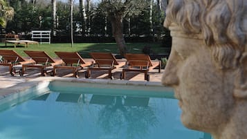 A pool area with lounge chairs and a stone sculpture.