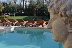 A pool area with lounge chairs and a stone sculpture.
