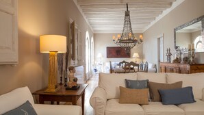 Ein Wohnzimmer mit einem weißen Sofa, einer Kristallleuchter und einer Holzbalkendecke.