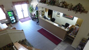 Un espace d’accueil comprenant un bureau, un ordinateur, une plante et un escalier.