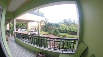 Un balcón con vista a una zona residencial, que incluye coches aparcados y vegetación.