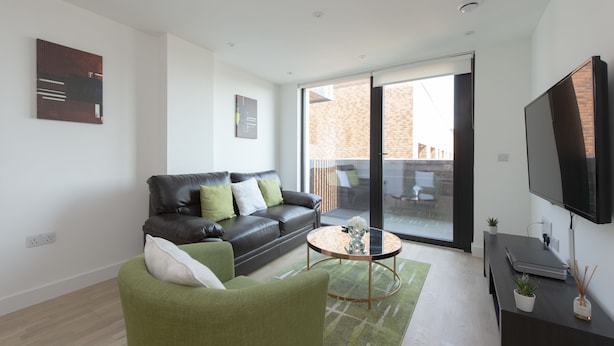 A modern living room with a leather sofa, green armchair, and a coffee table. - Fortified Apartment (Chelmsford)