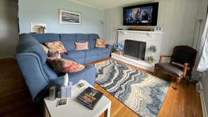 A living room with a blue sofa, a fireplace, a television, and a patterned rug. - SPACIOUS country home, Sleeps 6 adults  (Nicholasville)