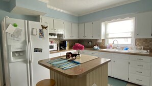 A kitchen with a central island, two stools, a refrigerator, and a window with blinds. - SPACIOUS country home, Sleeps 6 adults  (Nicholasville)