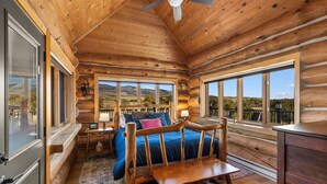 Une chambre située dans un chalet en rondins, avec un lit en bois, une table de chevet, une lampe et une vue sur les montagnes.