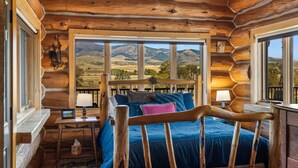 Une chambre située dans un chalet en rondins, avec un lit, des tables de chevet et une vue sur les montagnes.