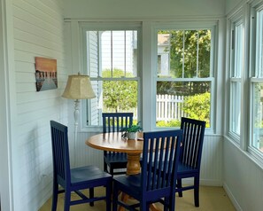 A room with a round wooden table surrounded by four blue chairs, a lamp, and a painting on the wall. - Charming Cottage Two Blocks from Downtown (Green Lake)